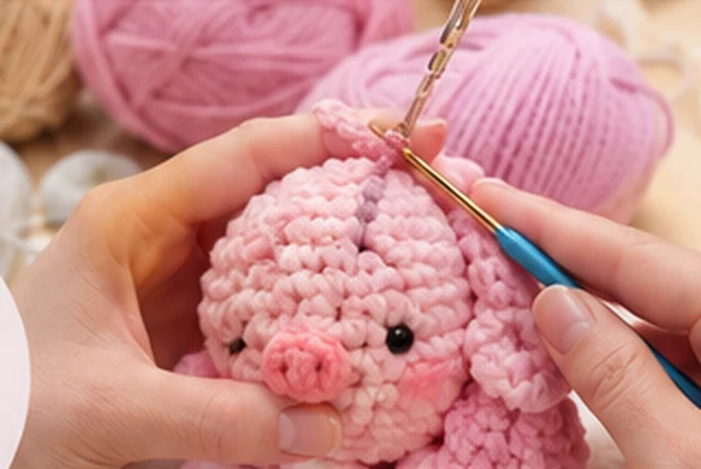 Manos tejiendo un cerdito a crochet